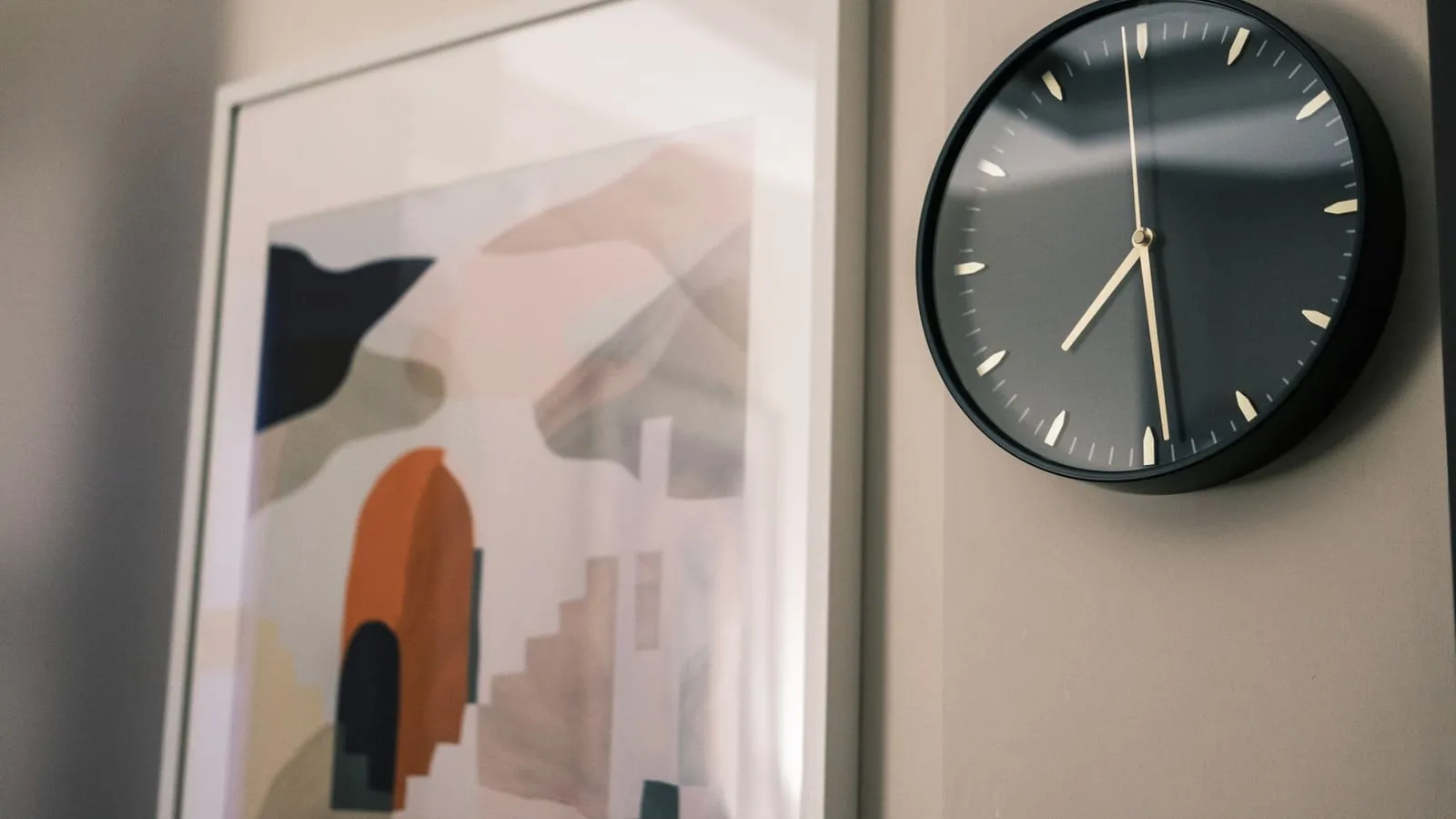 A minimalist wall clock and abstract painting in a modern interior setting.